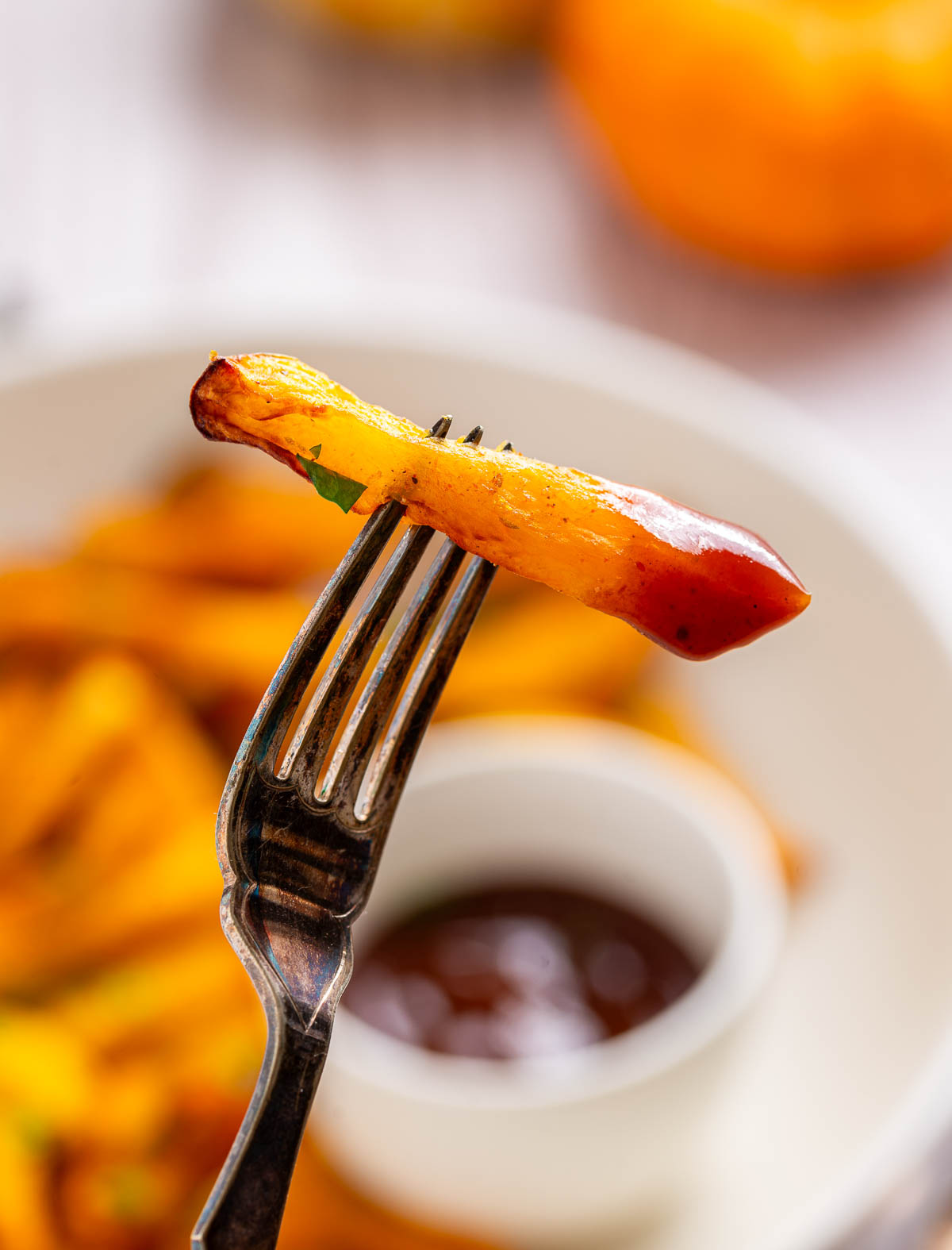 One pumpkin french fry dipped into a bowl of ketchup.
