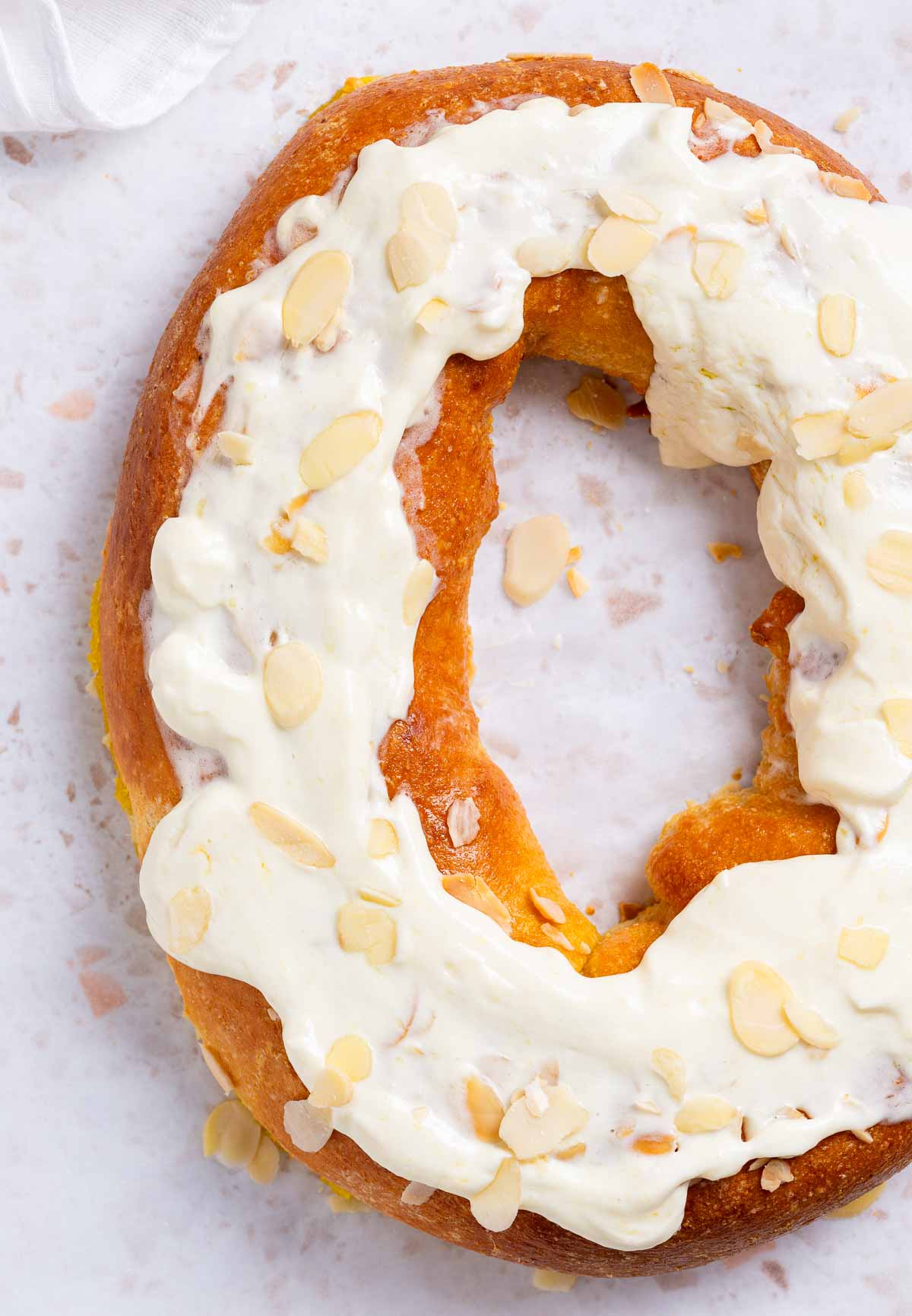 A  keto pumpkin kringle danish is a pastry ring with a pumpkin cream filling, and cream cheese frosting with sliced almonds for garnish.