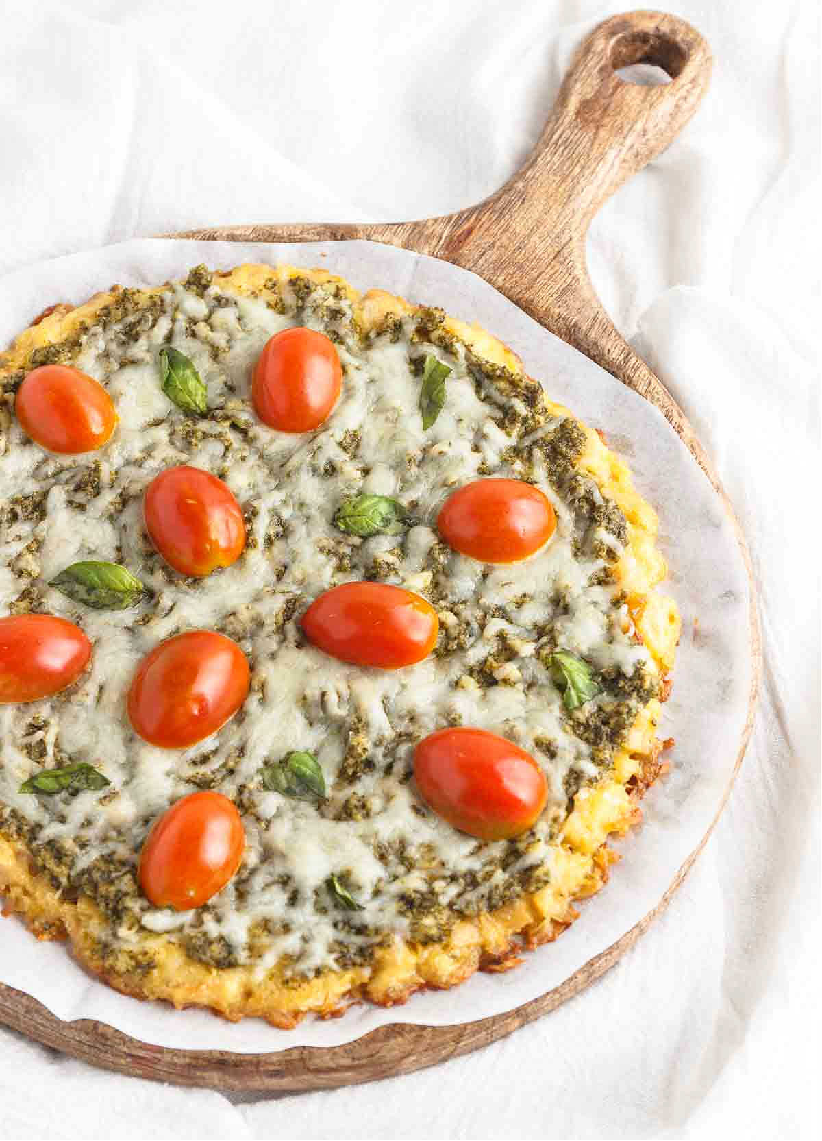 A low-carb pesto pizza on a chicken crust with tomato and basil.