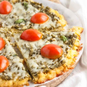 A low-carb pesto pizza on a chicken crust with tomato and basil.