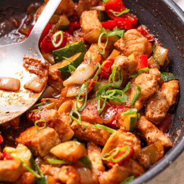 A pan of Keto Sweet and Sour Pork with a large spoon.