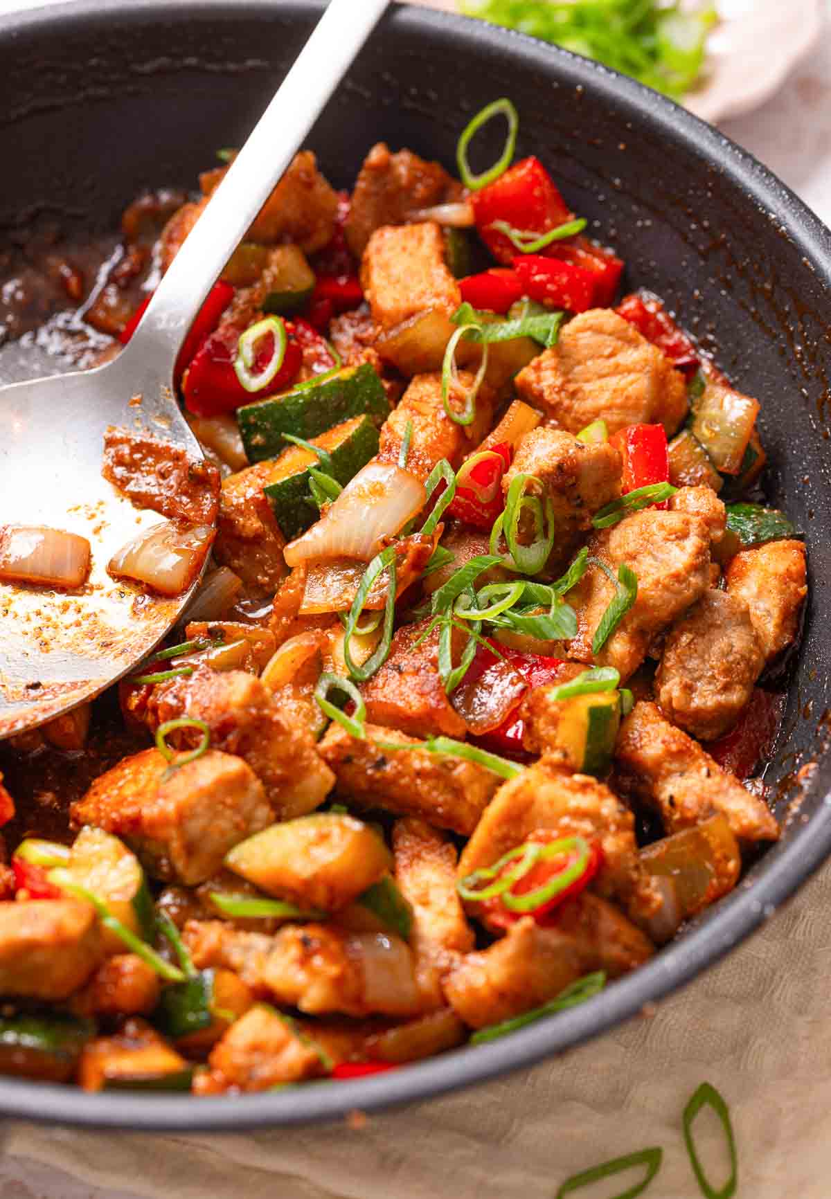 A pan of Keto Sweet and Sour Pork  with a large spoon.