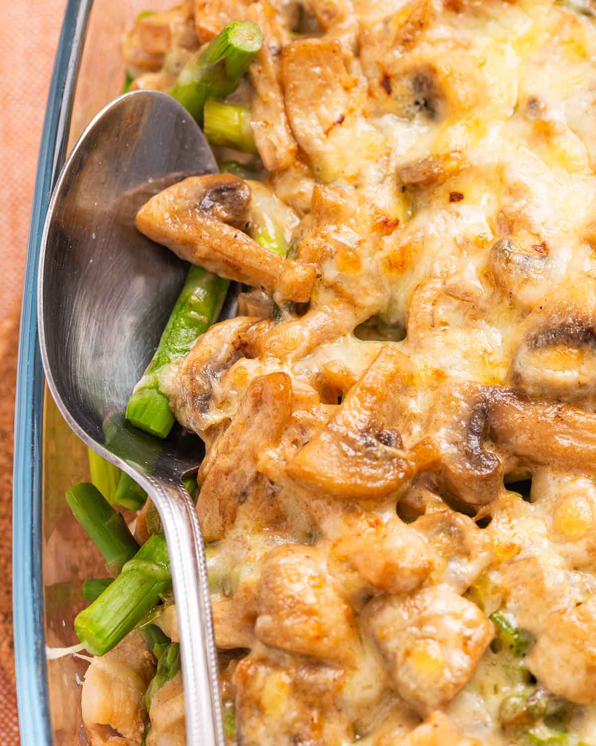A cheesy casserole with chicken, asparagus, and mushrooms in a creamy sauce.