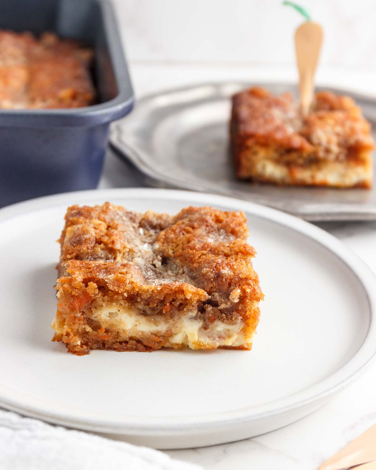  A square of Low Carb Carrot Coffee Cake with a pan of cake behind it.