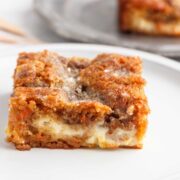 A square of Low Carb Carrot Coffee Cake with a pan of cake behind it.