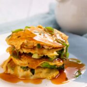 A stack of egg foo young patties covered in gravy.