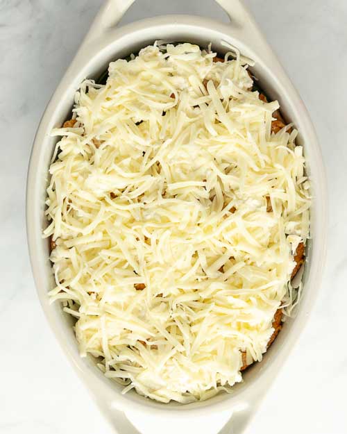 Topping the casserole wih cheese.