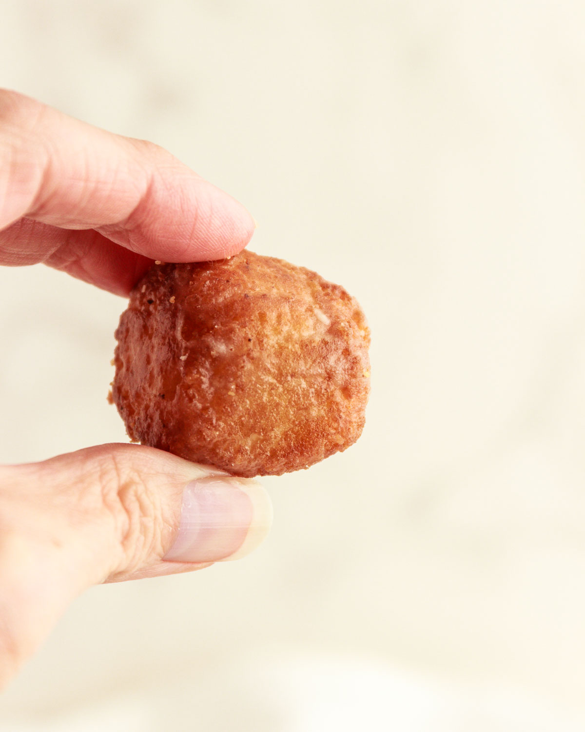 A hand holding up a keto donut hole.