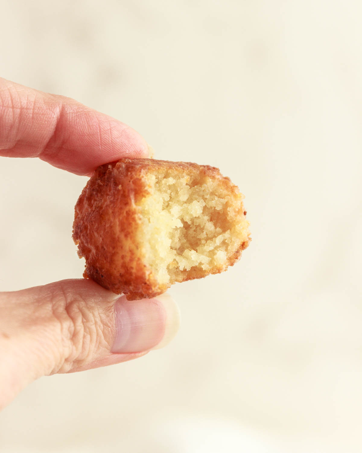 A hand holding up a keto donut hole with a bite in it.