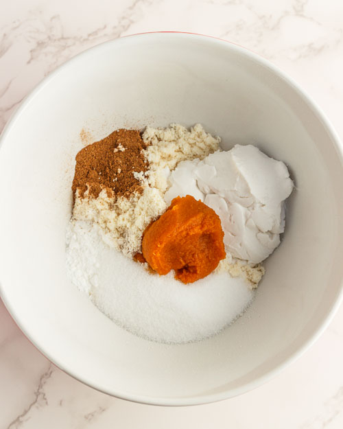 Adding the donut hole ingredients to a bowl.