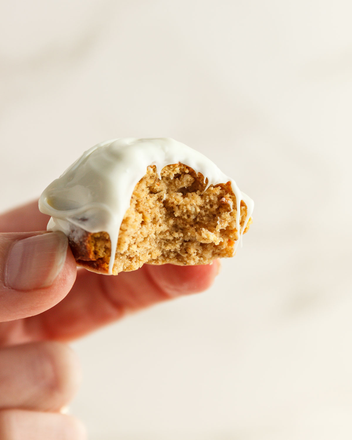 Pumpkin donut hole with a bite in it held by a hand.