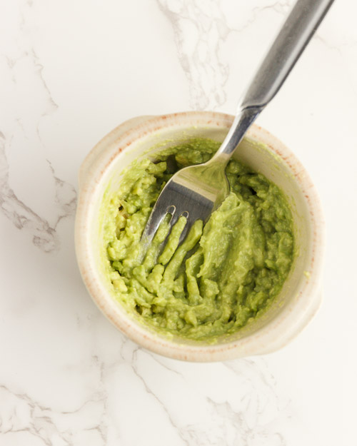 Scrambling an egg and mashing the avocado.