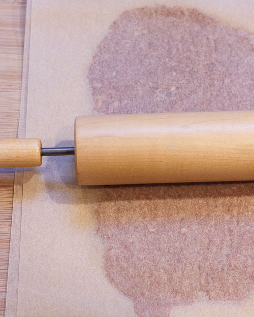 Place the meat mixture between two large sheets of parchment paper. 