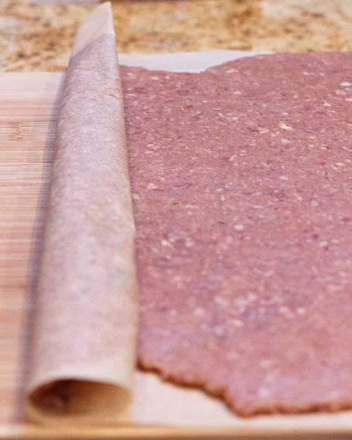 Removing the parchment paper from the top of the meat.
