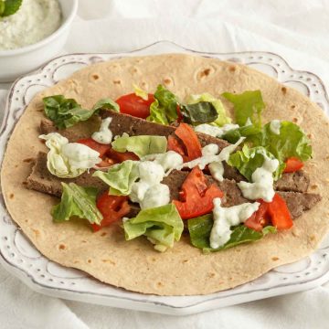 Beef gyro meat with veggies and tzatziki sauce on a low carb wrap.