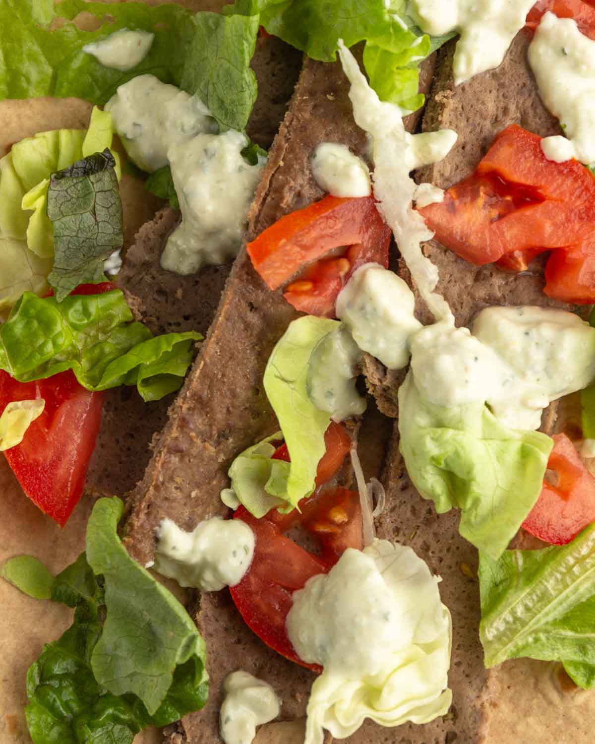 Beef gyro meat with veggies and tzatziki sauce on a low carb wrap.