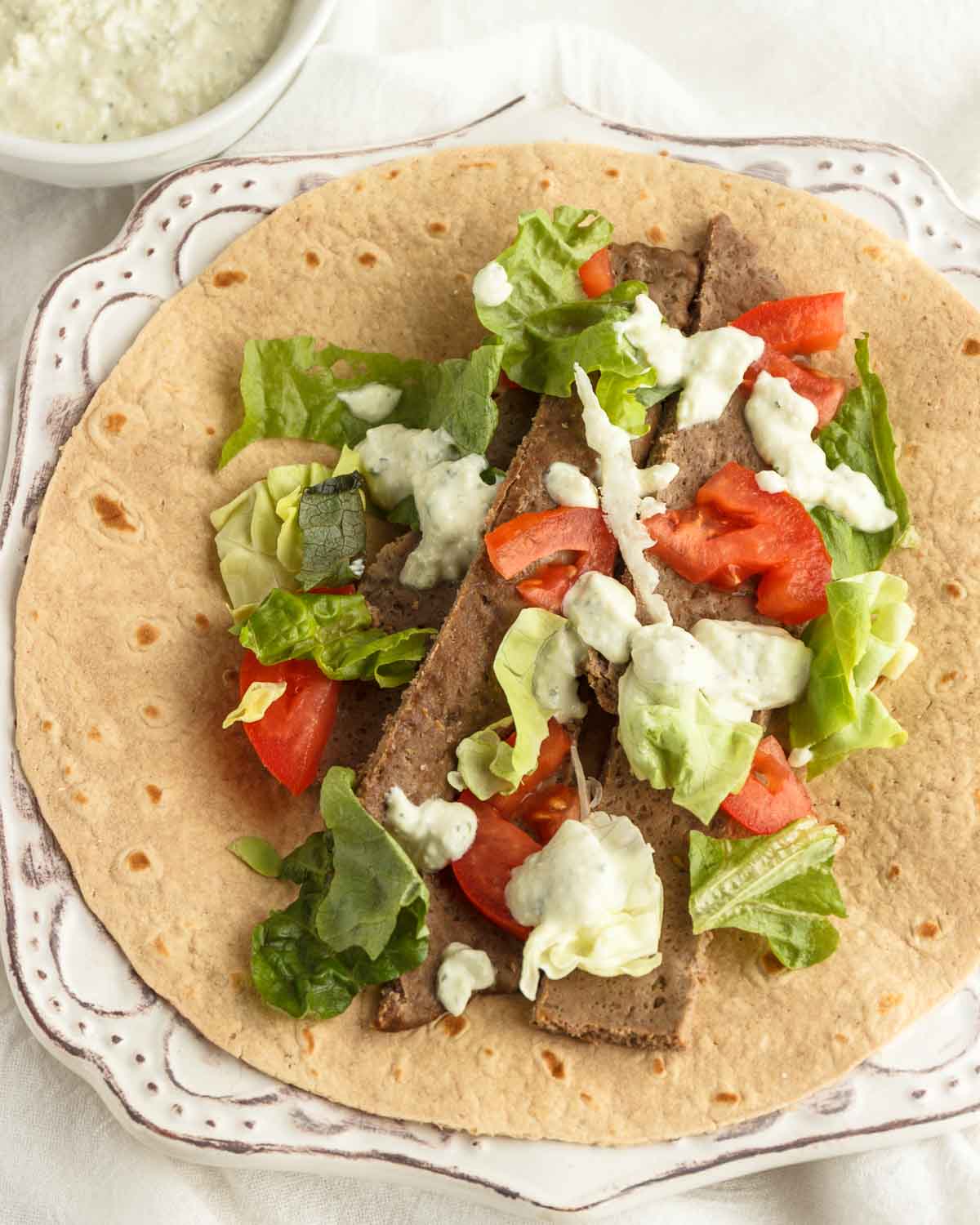 Beef gyro meat with veggies and tzatziki sauce on a low carb wrap.