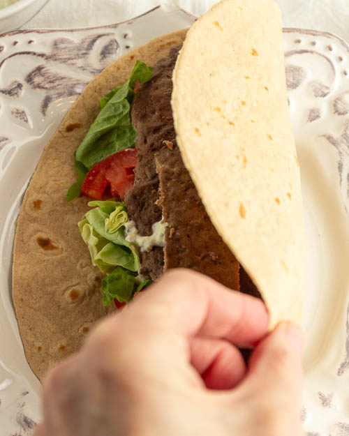 Add the gyro meat to a flatbread and top with veggies and sauce.