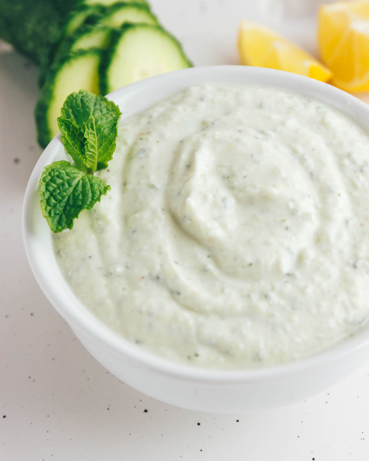 Homemade Tzatziki Sauce with a mint garnish in a white bowl.