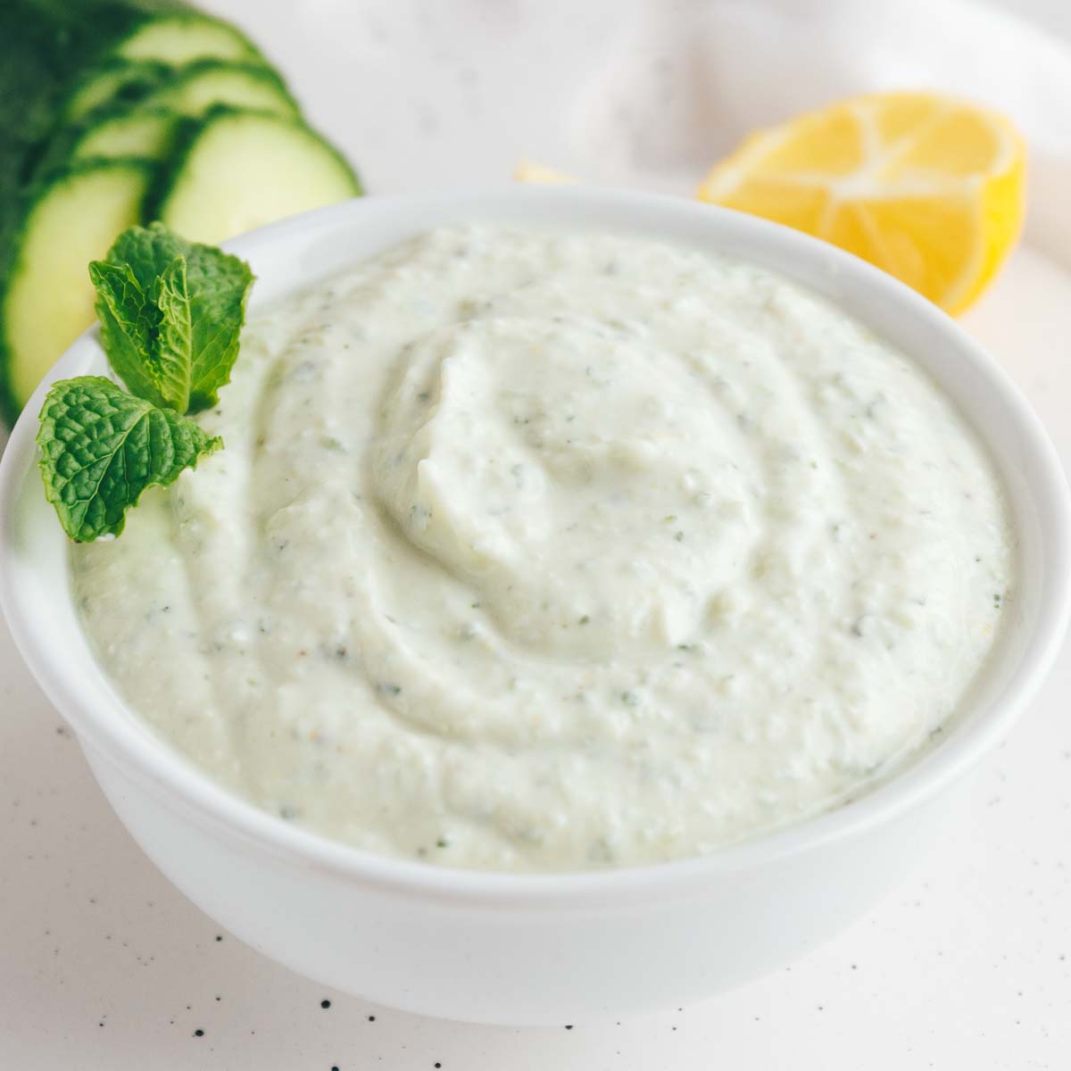 Homemade Tzatziki Sauce with a mint garnish in a white bowl.