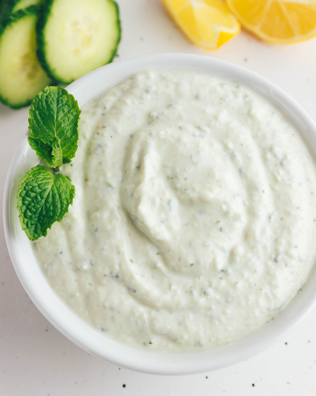 Homemade Tzatziki Sauce with a mint garnish in a white bowl.