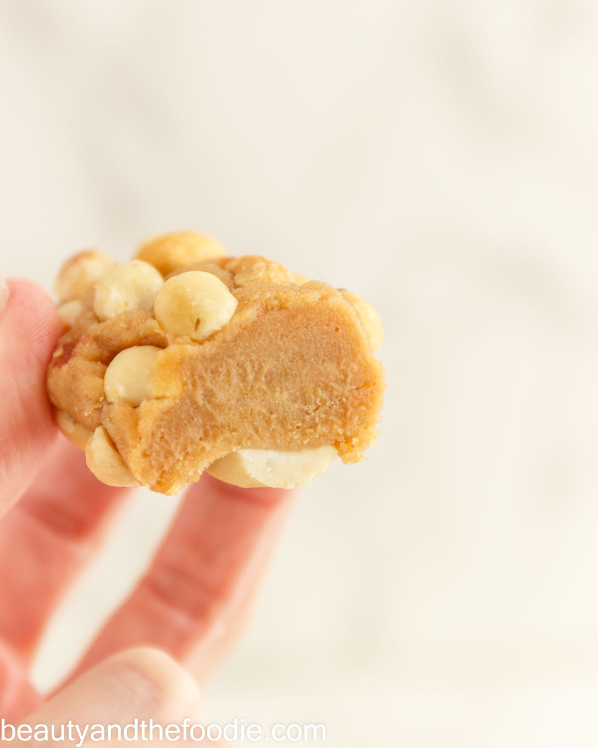 A keto payday bar held in a hand with a bit out of it.